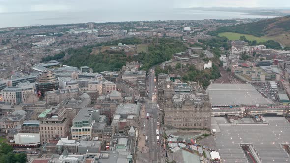 Dolly forward drone shot over Princes street towards Calton hill late evening alt