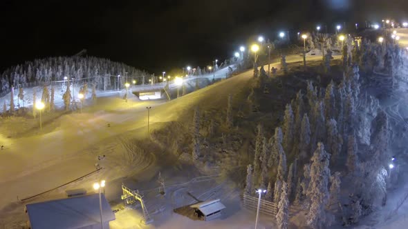 Flying over ski slopes and working lift at night alt