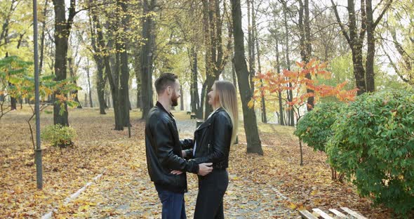 Lovely Couple Rejoices While Stands in Embraces and Caresses in Autumn Park alt