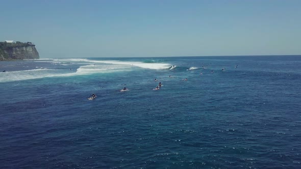 Drone View Over Blue Ocean Full of Surfers Enjoys Paddling and Riding Waves. alt