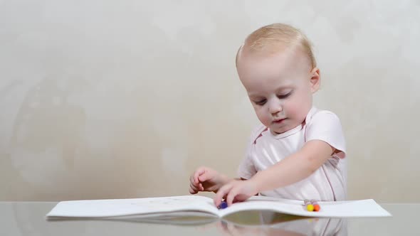 baby girl draws, drawing and laying out crayons on an album alt