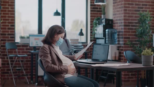 Pregnant Employee with Face Mask Using Laptop to Work alt