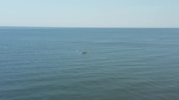 AERIAL: Blue Boat in the Sea on a Sunny Day with Fisherman Catching Fish alt