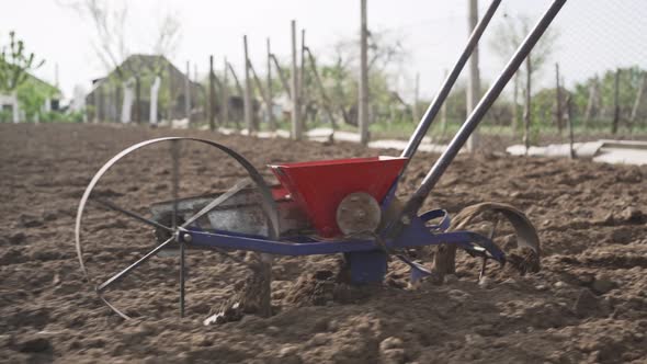 Man Planting Seeds in the Garden Using a Seeder