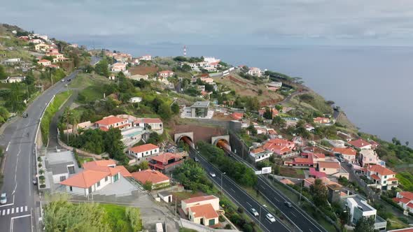 Aerial View of Tunnels and Winding Roads with a Seascape in the Background alt