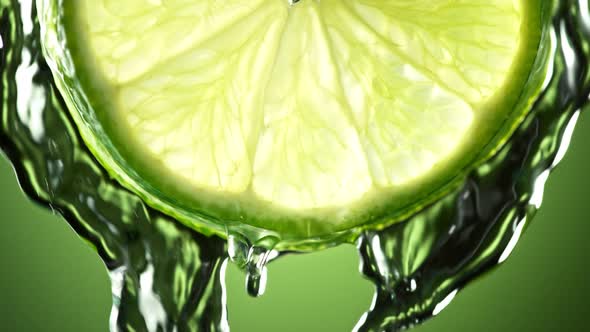 Super Slow Motion Macro Shot of Flowing Water From Lime Slice on Green Background at 1000Fps alt