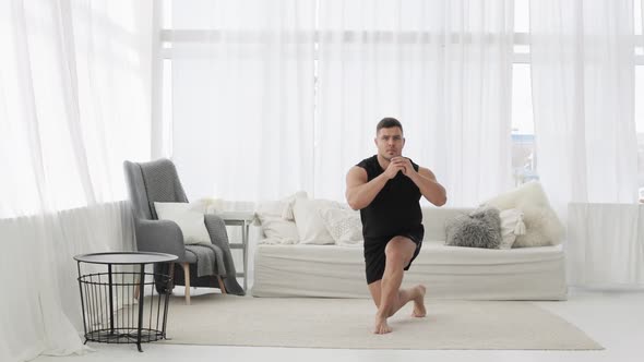 Sportive Young Man Is Doing Lunge Squat Exercise in Jump in Living Room at Home.