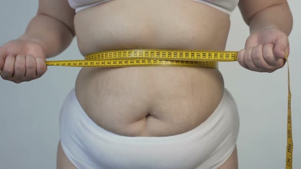 Body Hatred, Corpulent Woman Measuring Her Belly and Tightening Tape-Line, Diet alt