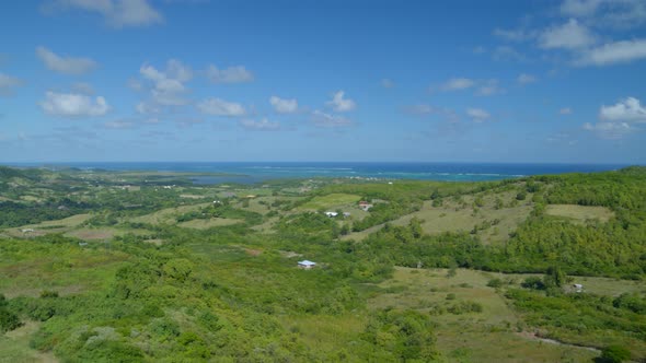 Aerial of green rolling landscape overlooking sea at a distance alt