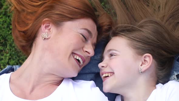 Little girl with mom relaxing in summer city park. alt