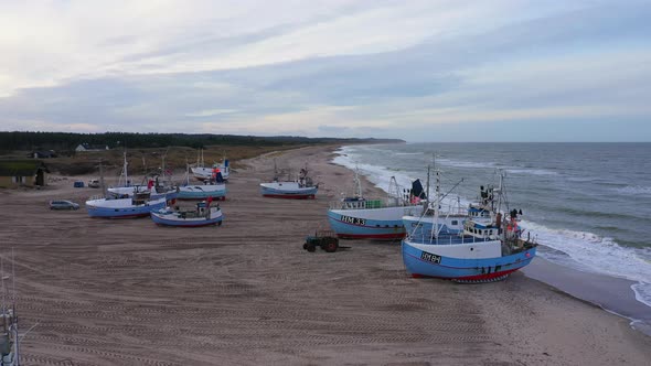 Aerial Over Fishing Boats Standing Ashore on a Sandy Beach on an Overcast Day alt