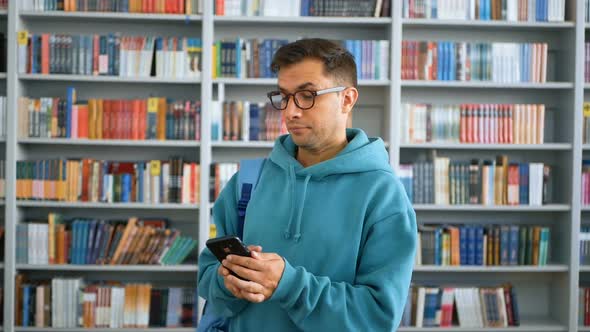 Closeup Portrait of a Young Attractive Student Guy He is Texting with Friends on His Smartphone