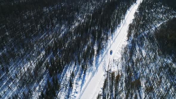 Aerial View of Car Driving Through Winter Forest Back Road. Scenic Winter Landscape