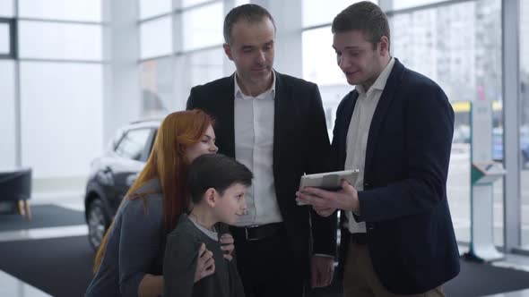 Caucasian Family Talking with Car Dealer in Showroom alt