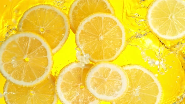 Super Slow Motion Shot of Lemon Slices Falling Into Water on Yellow Background at 1000Fps. alt
