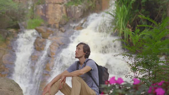 A Young Man Tourist Visits Waterfall in Mountains. Travel To Dalat Concept alt
