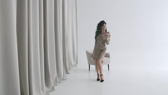 Sensual Woman Posing in a White Room with a Gray Chair. Attractive Brunette Walks Around the Room in alt