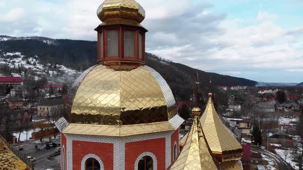 Aerial Drone View of Ukrainian Church with Golden Domes in Carpathian Village in Winter alt