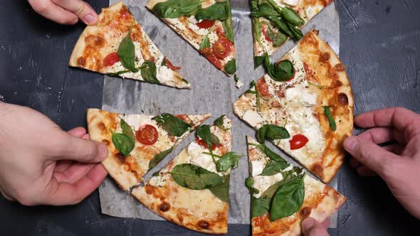 Pizza top view. Hands pick up pieces of hot pizza close-up slow mo