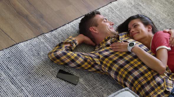 Cute couple relaxing together on floor mat in living room at home 