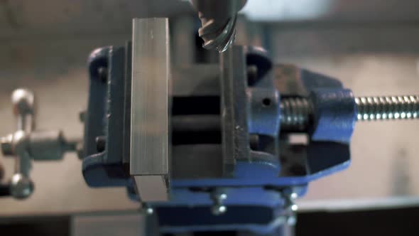 The worker fixes the metal structure in a vise at the plant. Close-up