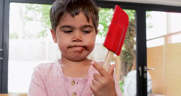 Boy licking chocolate cream from spatula