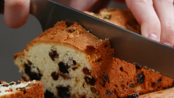 The Man Cuts a Soft Piece of Raisin Muffin and Lays It on a Wooden Chopping Board in the Home