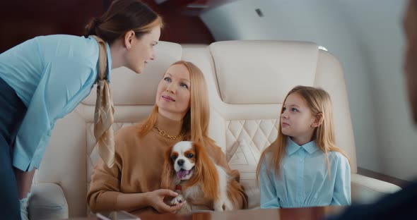 Flight Attendant Taking Order From Family in First Class Airplane Interior alt