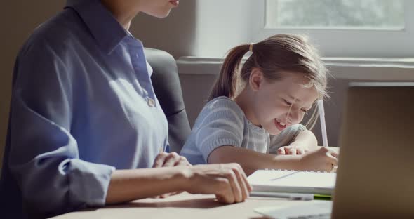 Child Daughter and Mum Sitting at Table Together, Study at Home, Girl Tired of Doing Homework alt