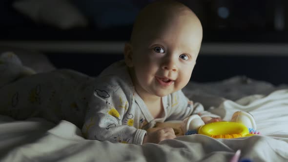 portrait of a baby boy in bed at night in the light of a lamp