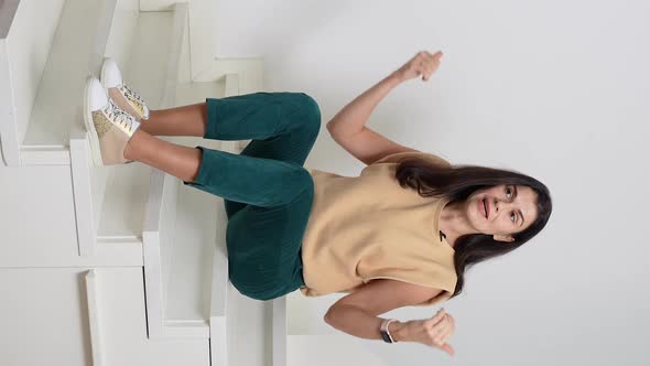 Vertical Screen Woman Sitting on Stairs and Giving Speech to Camera alt