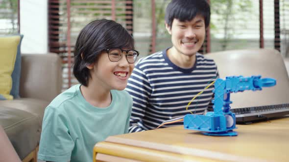 Asian kids program robotic cranes with laptops to learn about technology