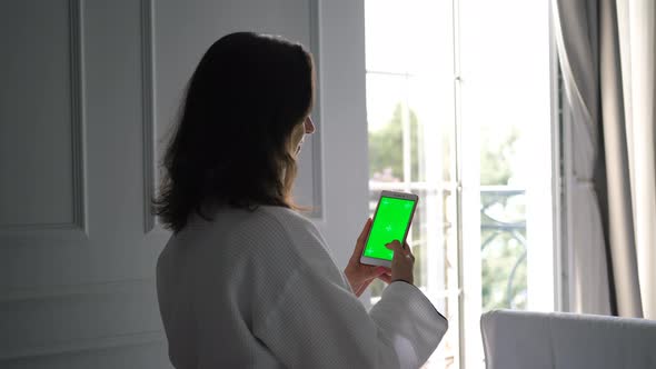 Woman in Bathrobe Using Phone with Green Screen alt