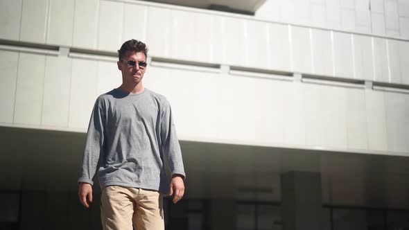 Handsome Caucasian Cool Man in Sunglasses Is Walking Along the City Street alt