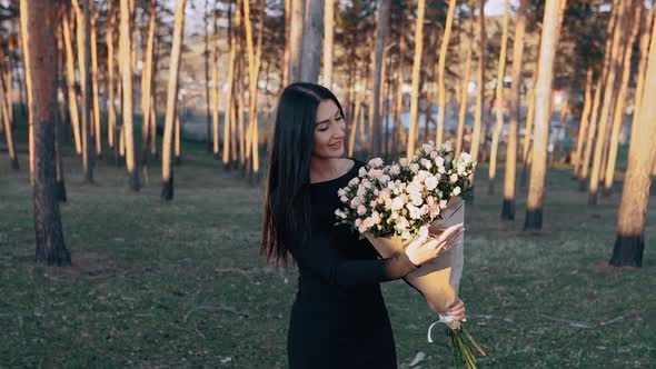 The Portrait of a Charismatic Young Woman in Nature Holding a Bouquet of Beautiful Flowers in Her alt