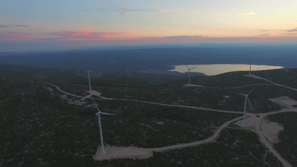 Aerial view of five windmills for the production of electric energy, at sunset alt