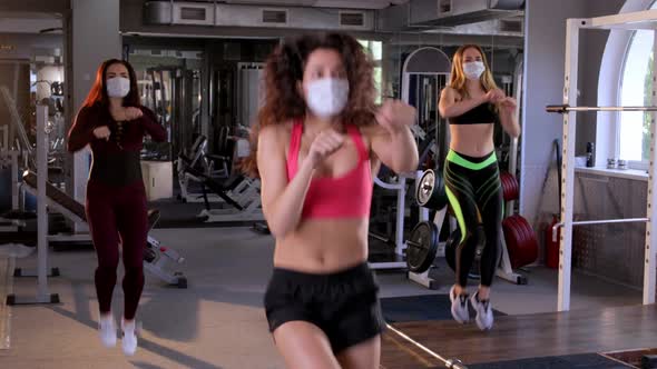 Group of Young Beautiful Female Athletes Wearing Face Masks Doing Boxing Warm-up Aerobics in the Gym