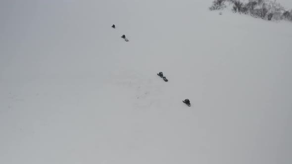 A Group of Extreme Tourists Ride Snowmobiles on a Frozen River