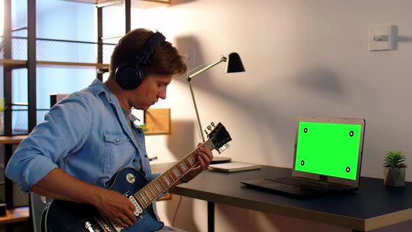 Man in Headphones Playing Bass Guitar at Home alt