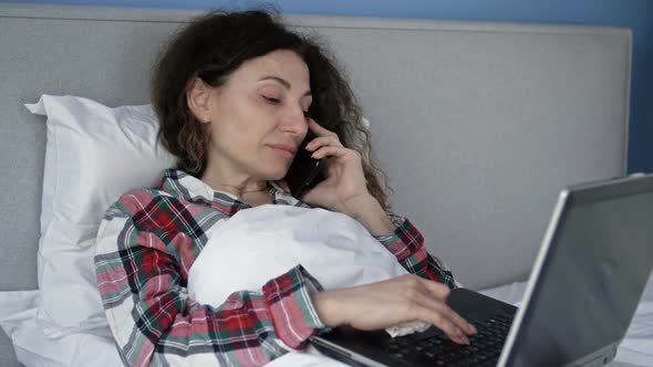 Sick Woman Lying in Bed with Laptop Computer and Smartphone in Self Isolation
