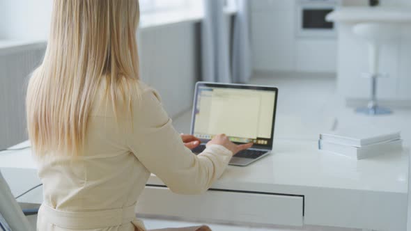 Young girl working at a laptop at home office. Young woman typing on laptop at the desk alt