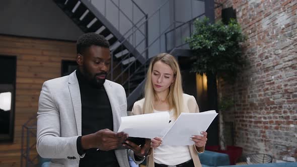 Businessman Revisioning Different Documents with His Blond Stunning Female Colleague alt