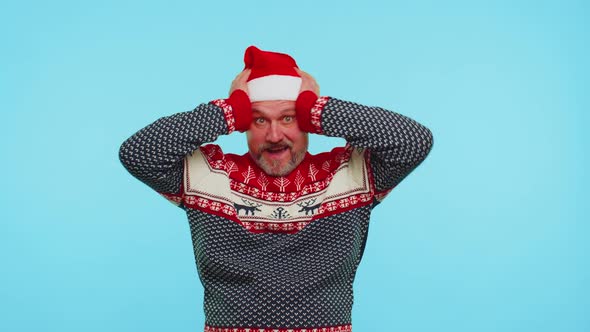 Man Wears Red New Year Deer Sweater Raising Hands in Surprise Shocked By Sudden Victory Wow Emotion alt