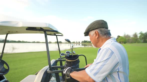 4K Portrait of Asian senior man golfer standing on golf course at summer sunset. alt