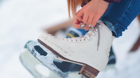 Girl and Man Lace Figure Skates To Rest on Ice Rink