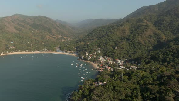 Bungalows And Boats At The Beachfront Of Yelapa Town Resort With Towering Forest Mountains In Jalisc alt