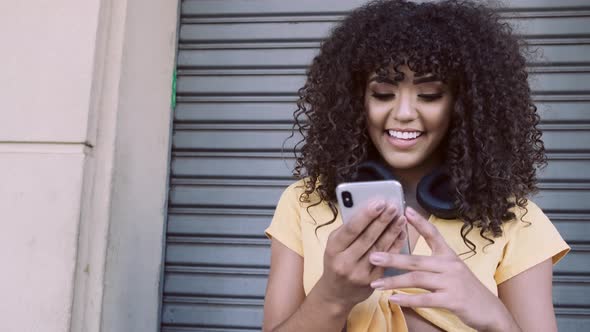 Beautiful Woman with Afro Curly Hair with Cell Phone and Headphones