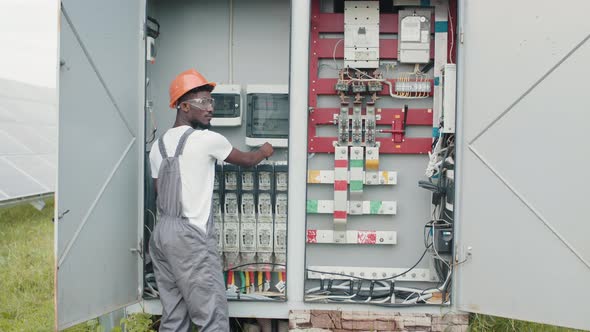 African American Man in Grey Overalls and Orange Helmet Repairing Cables in alt