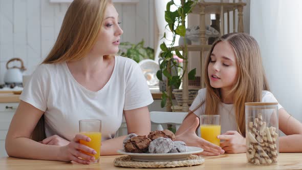 Mother and Daughter Teenager Child Girl Sitting Together at Table in Kitchen Drinking Natural Orange alt