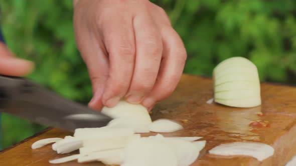 Male Hands Slicing Fresh White Onion on A Cutting Board alt